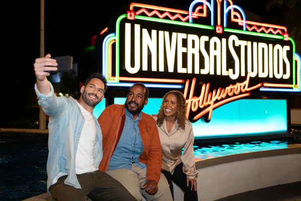 Three people posing for a selfie in front of the Universal Studios Hollywood sign