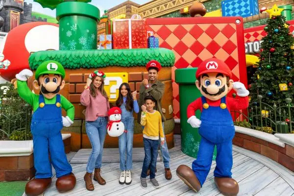Mario- and Luigi-themed snowmen together in front of a Christmas tree with ornaments, yellow stars and blocks.