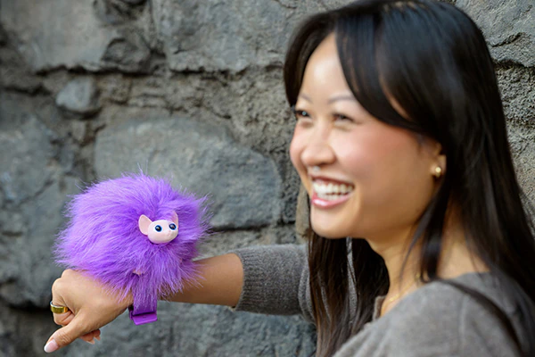 A woman smiling as she holds a Pygmy Puff on her wrist.