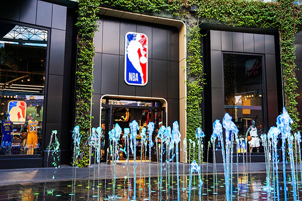 A store with a large NBA logo, ivy on the outer walls, uniforms in the windows, and colorful dancing fountains out front.