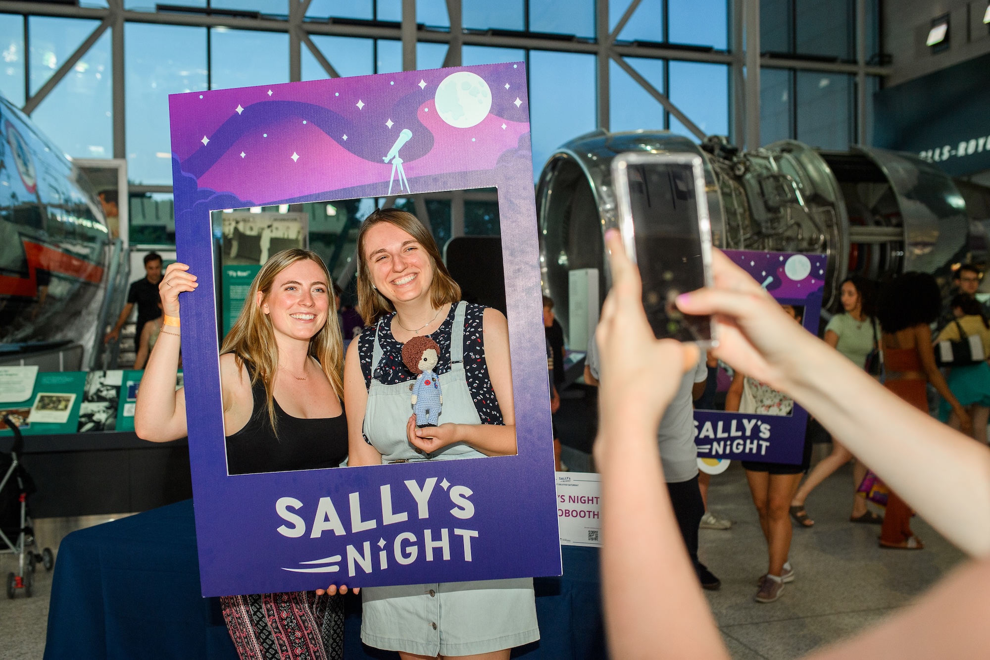 Two women take a photo in a Sally's Night photo frame.