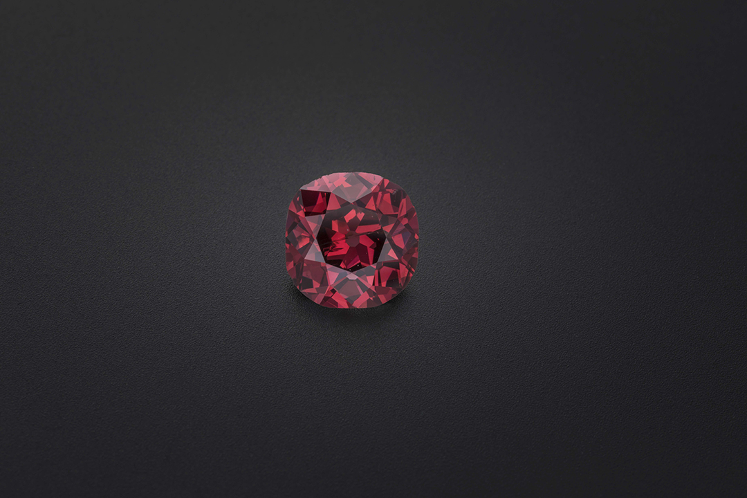 a round faceted red diamond on a black background
