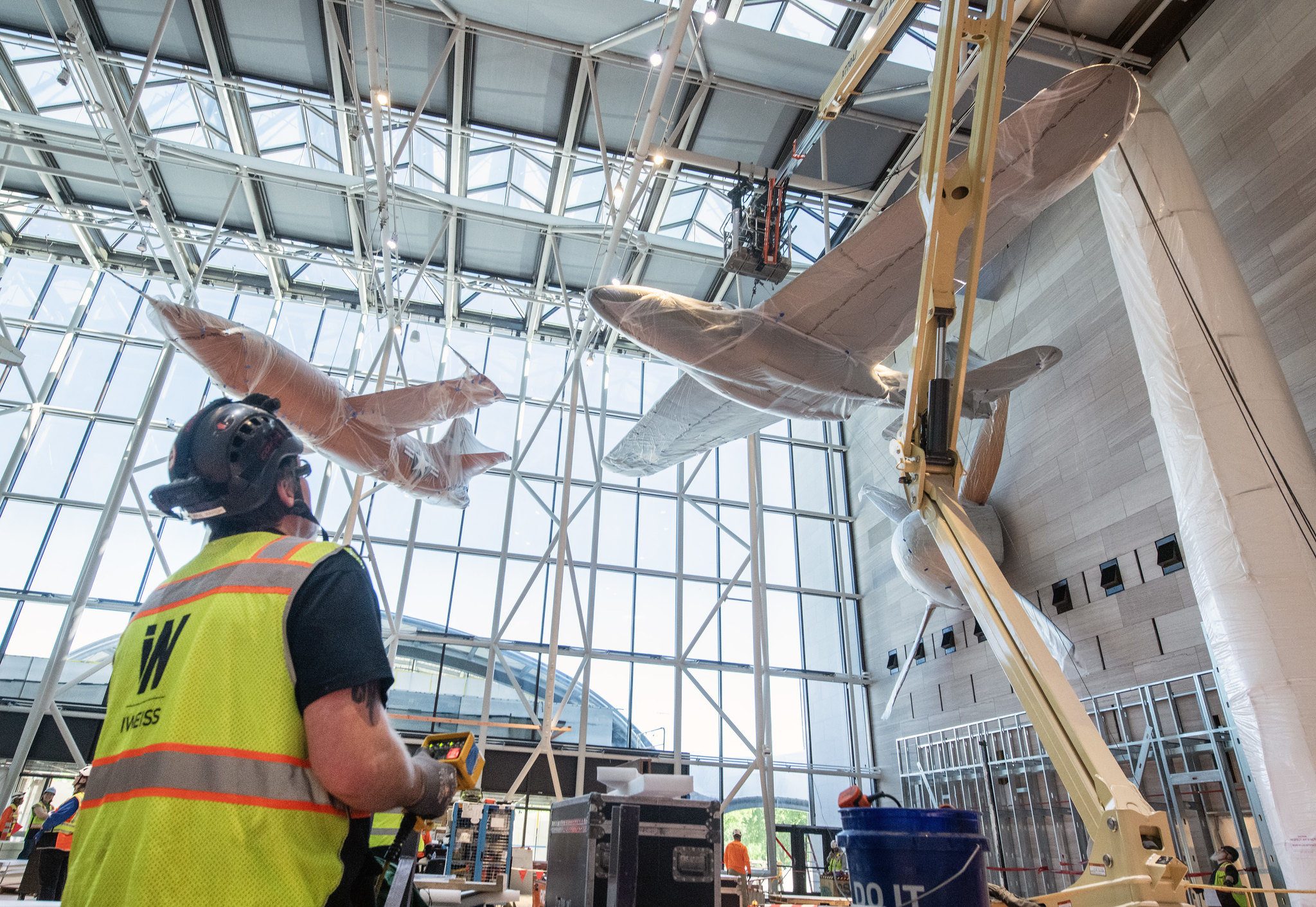 A man in a high-viz vest works to suspend an aircraft in the museum.