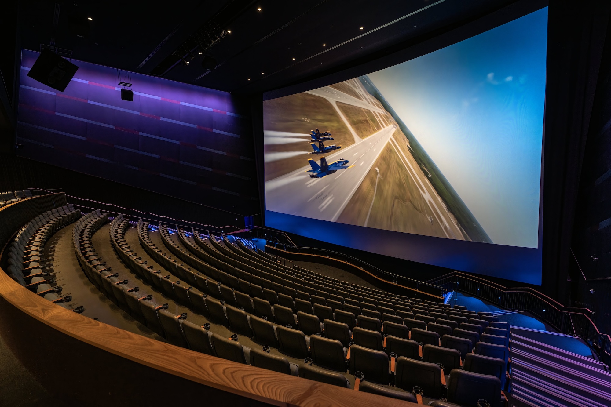 The inside of a theater is photographed while a movie plans on a big screen.