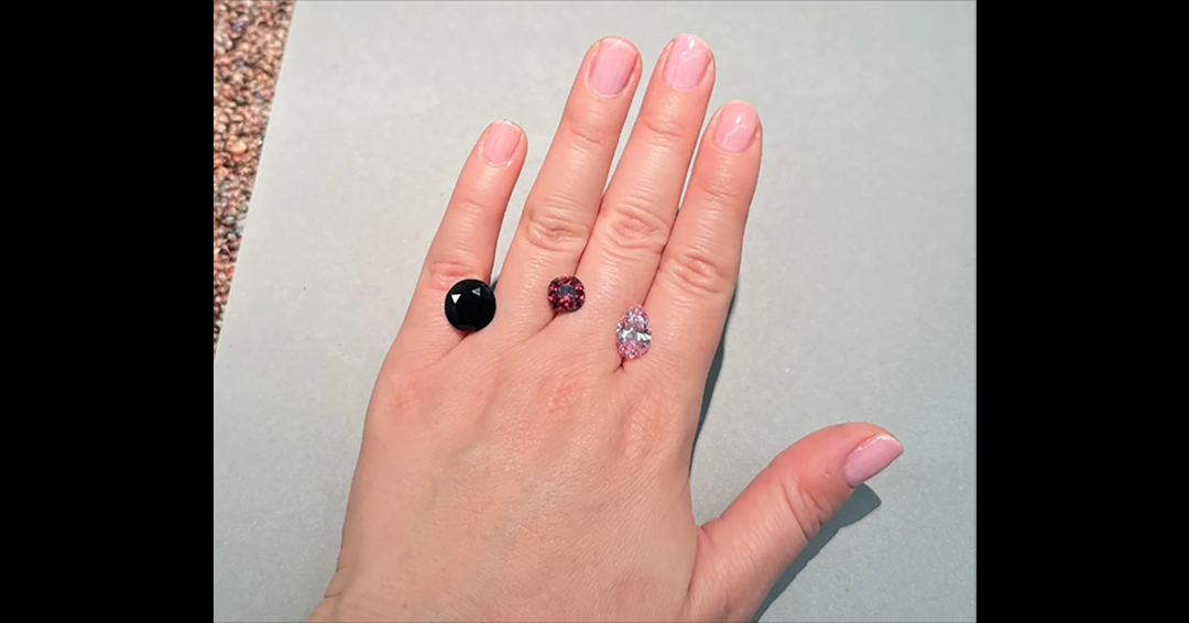 A human hand with 3 diamonds, each of a different color, between fingers