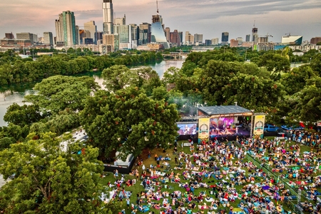 People gather in front of a stage in a park for a concert