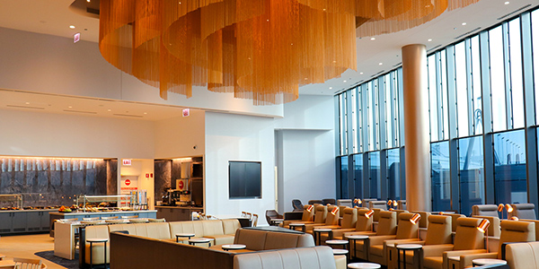A buffet serving area, seating and airfield views at the LOT Business Lounge at Chicago O'Hare International Airport