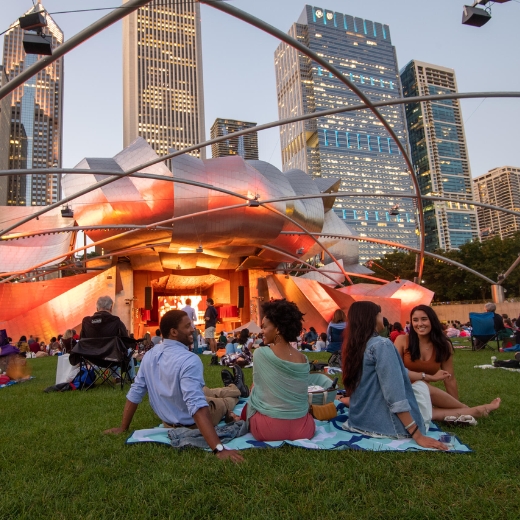 Audience members sit on the lawn in Millennium Park for a concert at the Jay Pritzker Pavilion