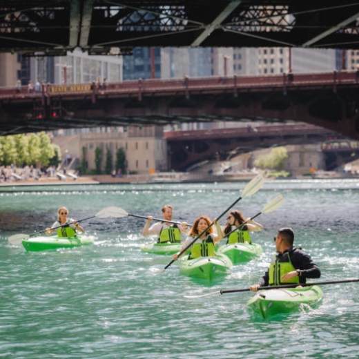 Five paddlers in neon green kayaks on the Chicago River downtown