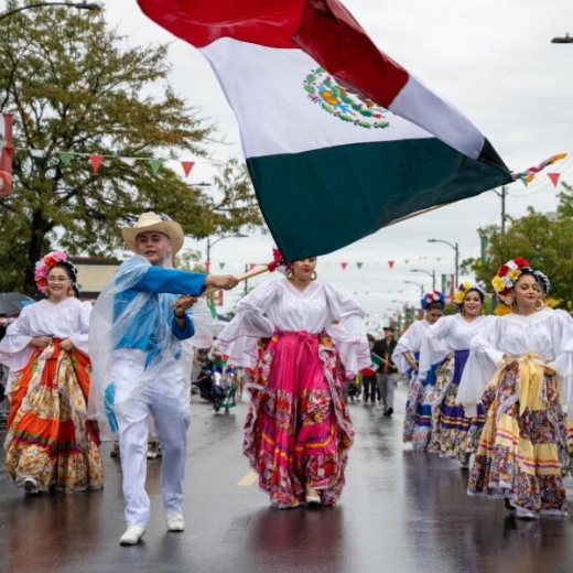 Marchers in colorful costumes wave a Mexican flag during the 26th Street Mexican Independence Day Parade in Chicago's Little Village neighborhood