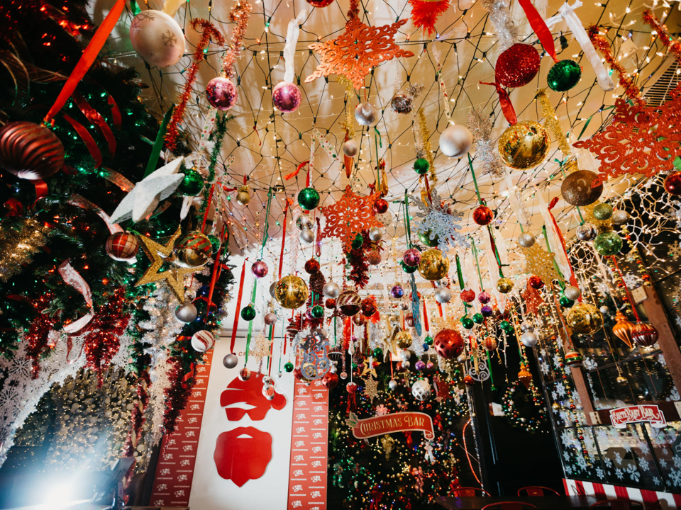 A festively decorated bar featuring colorful ornaments and decorations hung from the ceiling by long ribbons