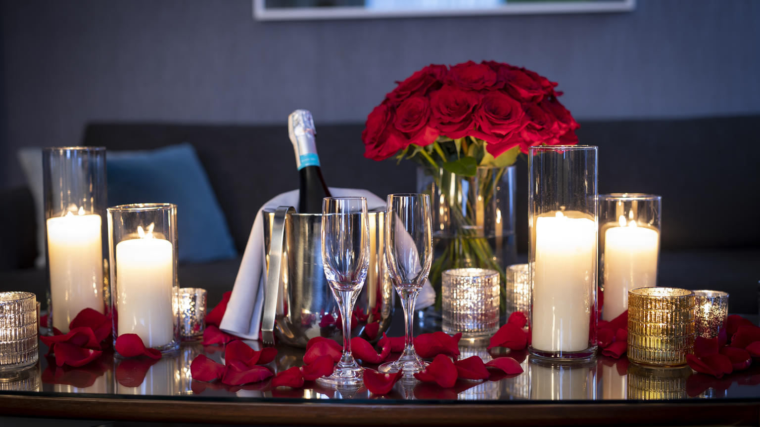 A table with champaign flutes, candles, and roses