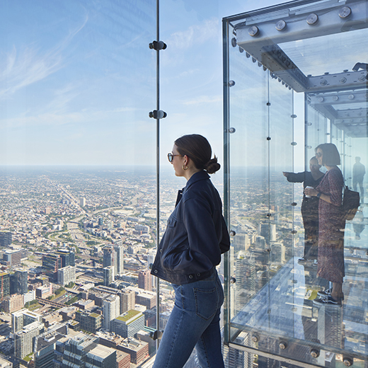 A woman gazes out at the city of Chicago from the Ledge at the Willis Tower.