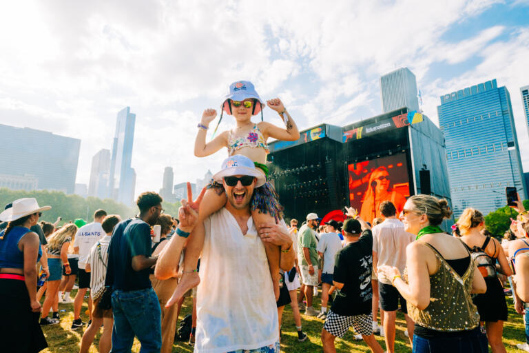 A man poses with a child on his shoulders at Lollapalooza