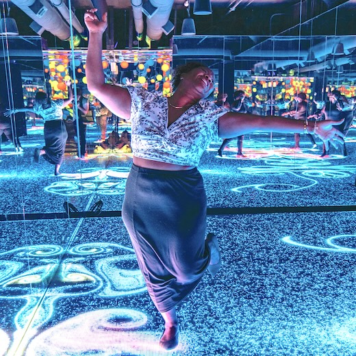 A woman dances in a blue-hued room and art installation inside WNDR Museum in Chicago