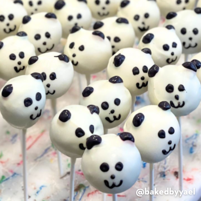 Rows of panda-themed cake pops with smiling faces on a white stand.