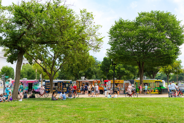 Food trucks lined up serving customers with trees above