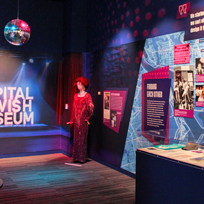 Gallery photo featuring the Welcoming Spaces section, featuring a disco ball, Ester Golberg’s drag costume and a photo mural of the museum’s name in lights.