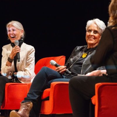  A stage view of two women, including legendary singer Joan Baez, participating in a panel or discussion.