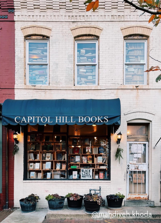 The storefront of Capitol Hill Books features a blue awning, a window full of books, and signs supporting social justice causes.