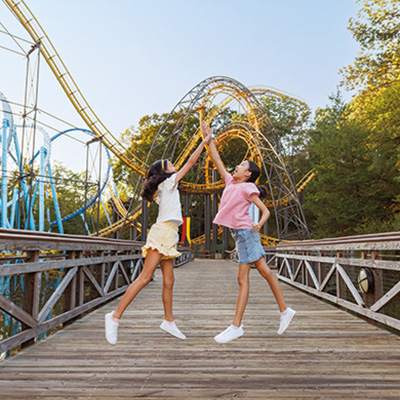 Kids high-five in front of a roller coaster at Busch Gardens® Williamsburg.