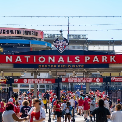 Fans in red gear enter Nationals Park through the Center Field Gate on a sunny day.
