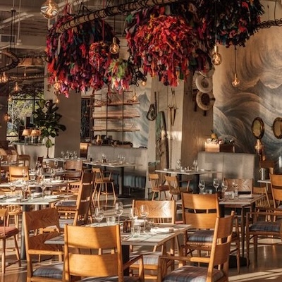 A warmly lit restaurant interior features wooden seating and vibrant ceiling decorations.