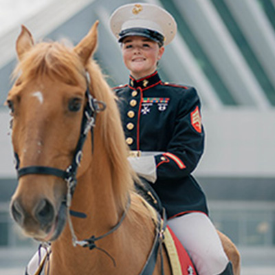 A U.S. Marine in formal dress uniform rides a horse during a ceremonial event in Washington, DC.