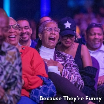 Audience members laughing and enjoying a comedy show at the Because They’re Funny festival.
