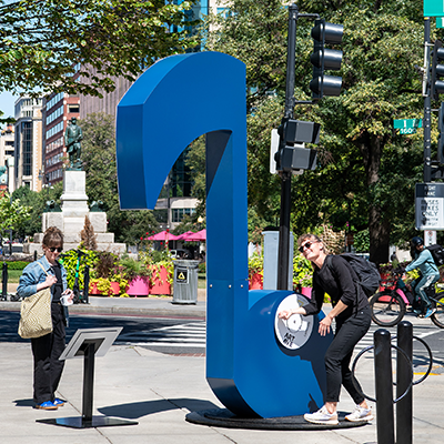 A visitor interacts with the blue Maestro sculpture by LeMonde Studio on Art Ave in Washington, DC.