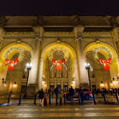 Large holiday wreaths with red bows decorate the entrance of Union Station in Washington, DC at night.
