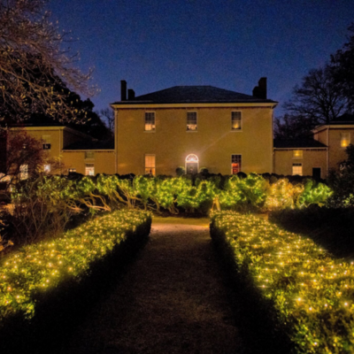 Holiday lights illuminate the garden walkway leading to the historic Tudor Place in Washington, DC at night.