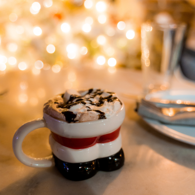 A festive holiday mug filled with hot cocoa topped with whipped cream and chocolate drizzle on a softly lit table in Washington, DC.