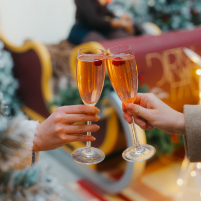 Two people clink champagne flutes garnished with cranberries in a festive holiday setting in Washington, DC.