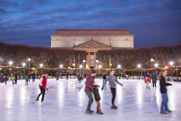 People ice skating at the National Gallery of Art Sculpture Garden rink in Washington, DC at dusk.