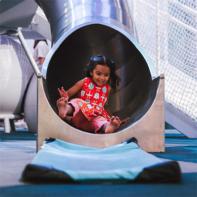 A young child slides out of a metal tube slide inside the National Children’s Museum in Washington, DC.