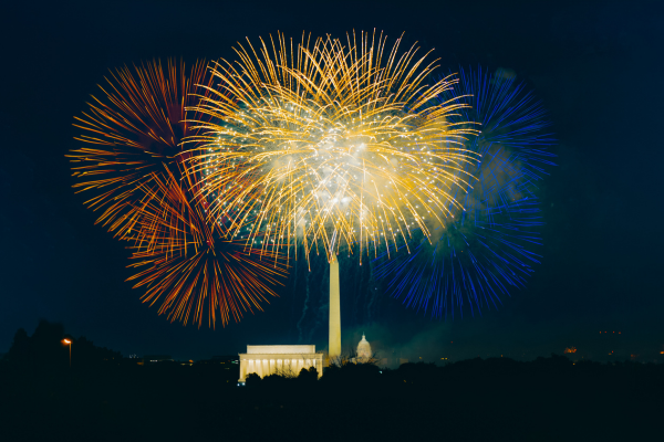 Colorful fireworks burst over the Lincoln Memorial and Washington Monument during a nighttime celebration in Washington, DC.