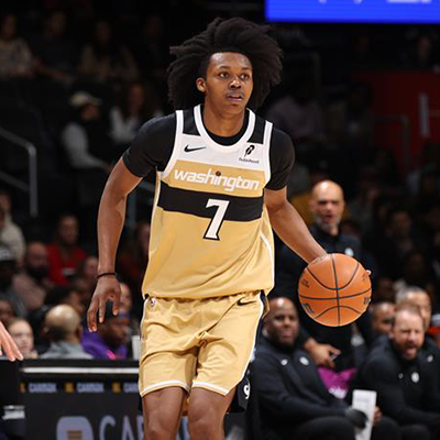 Professional basketball player in a Washington uniform dribbles the ball up the court during a game in Washington, DC.