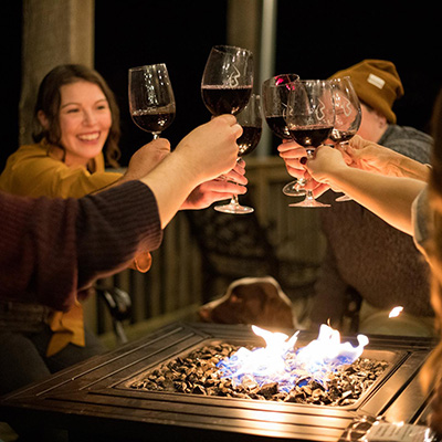 People around fire clinking their wine glasses to cheers at Bluemont Vineyards.