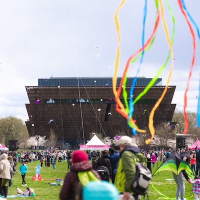People attend the Blossom Kite Festival in DC against the backdrop of the National Museum of African American History and Culture.