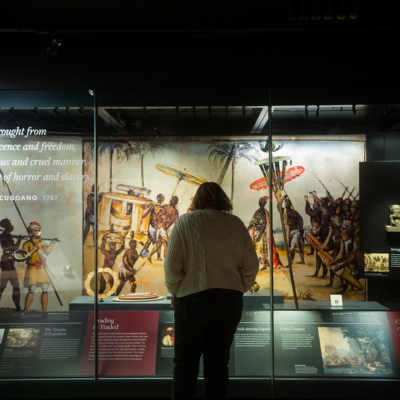 A visitor stands in a museum gallery viewing a large illustrated historical exhibit in Washington, DC.