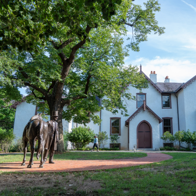 A statue of Abraham Lincoln stands on the front lawn of President Lincoln’s Cottage surrounded by trees on a sunny day in Washington, DC.