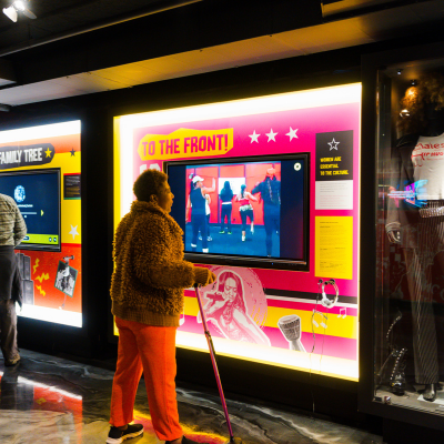 A visitor observes a colorful, tech-forward exhibit on Go-Go music.