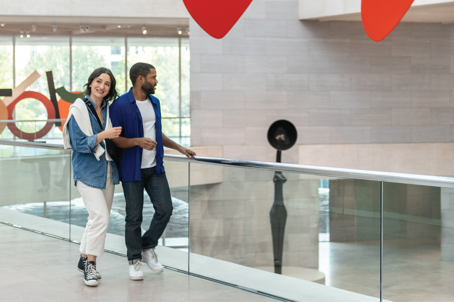 A couple walks through a modern atrium, admiring works at the National Gallery of Art.