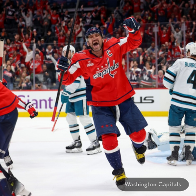 A Washington Capitals player (Ovechkin) celebrates a goal on the ice as fans cheer in the background.