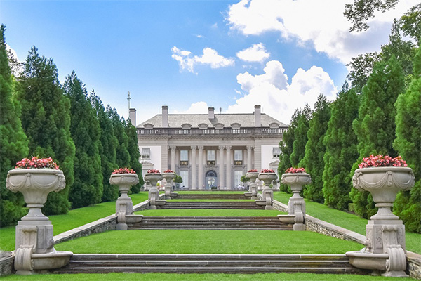 Exterior view of the Nemours Estate in Wilmington, Delaware, featuring a grand French-style mansion with formal gardens, fountains, and manicured lawns reflecting early 20th-century elegance.