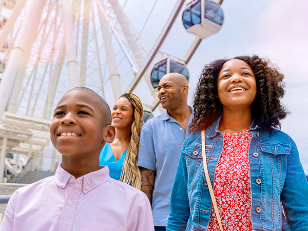 Family of four walking through the Waterfront District with the Capital Wheel in the background
