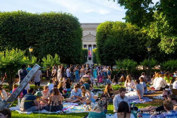 Crowds gathered on the lawn at the National Gallery of Art Sculpture Garden for Jazz in the Garden, sitting on blankets and socializing near the fountain.