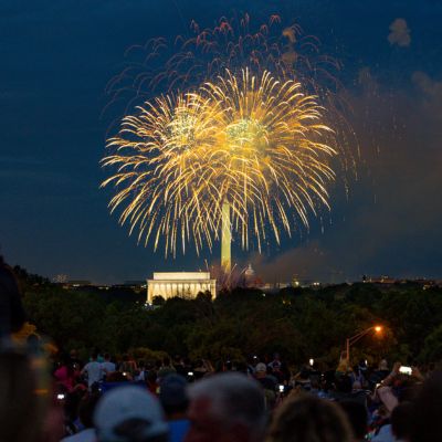 Spectators watch colorful fireworks burst above the Lincoln Memorial and Washington Monument during a nighttime celebration in Washington, DC.