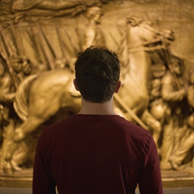Visitor viewing a large sculptural relief at the National Gallery of Art, standing in front of the detailed artwork inside a gallery space.
